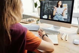 a person sitting at a desk watching training video on their computer